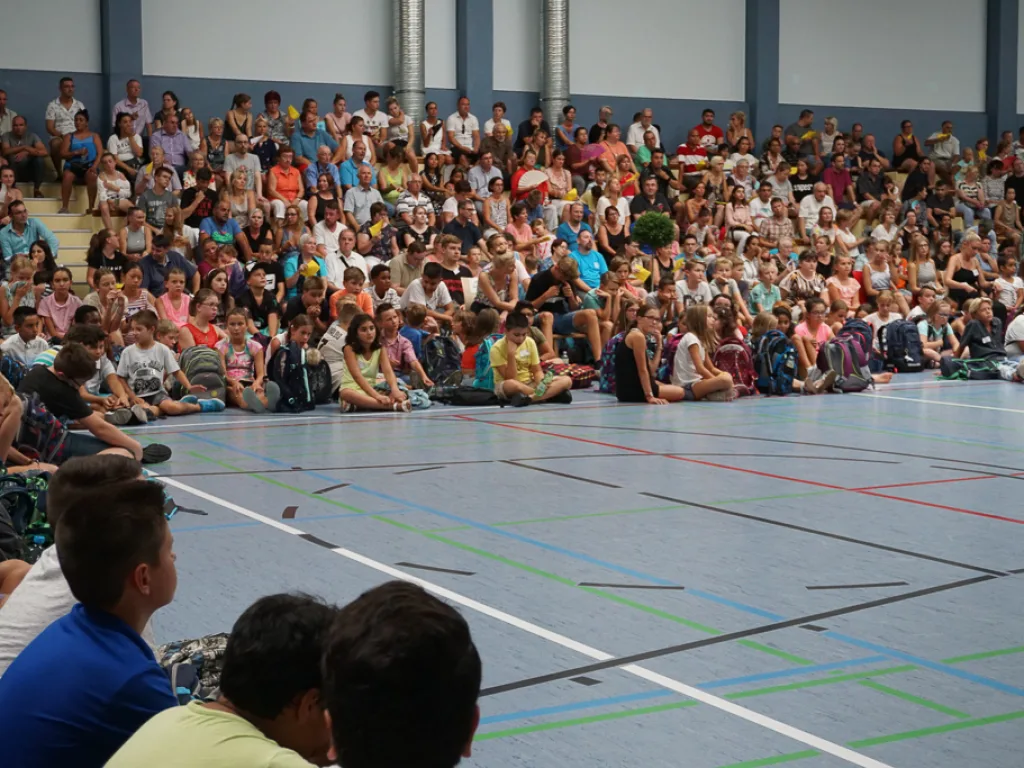 Kinder und Erwachsene sitzen dicht gedrängt.